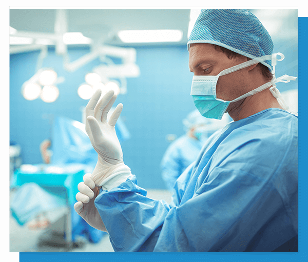 Image of a male surgeon putting on gloves in a hospital